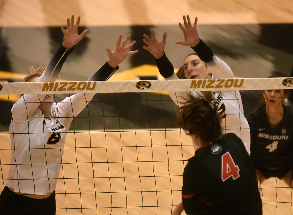 Sophomore Claudia Dillon and senior Kylie Deberg jump to block